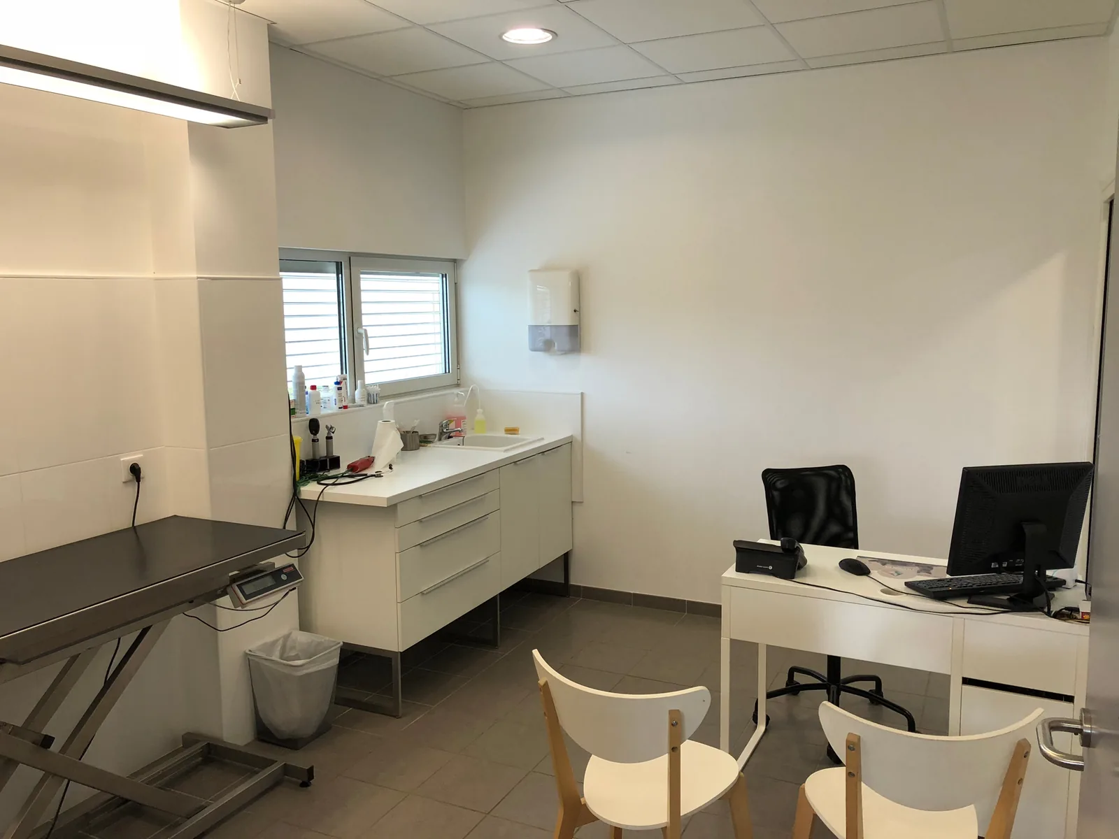 Salle de consultation de la clinique vétérinaire avec table d'examen élévatrice et bureau